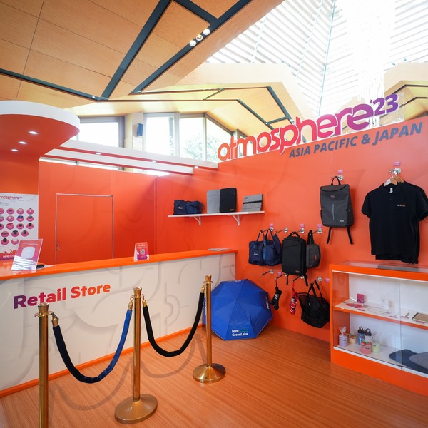 Atmosphere-23-Asia Pacific-Japan-PMG-4.jpg A vibrant orange wall with Atmosphere '23 merchandise on display.